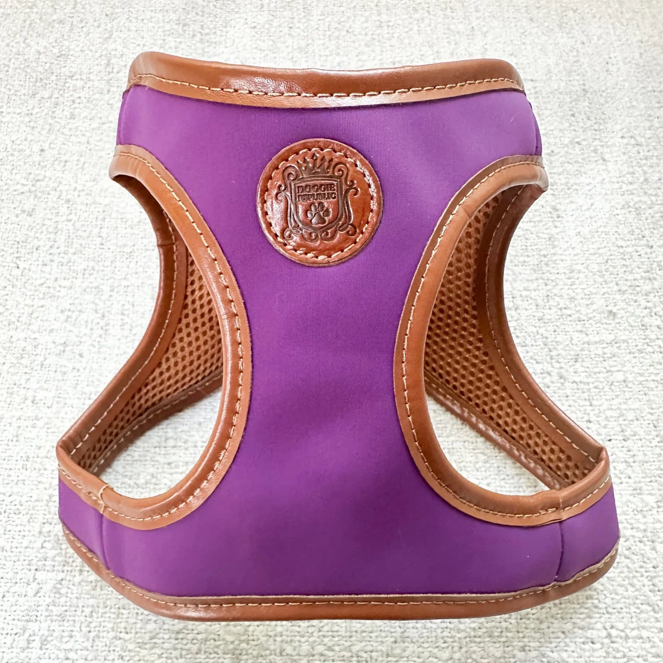 Purple dog harness with brown trim on a textured white background